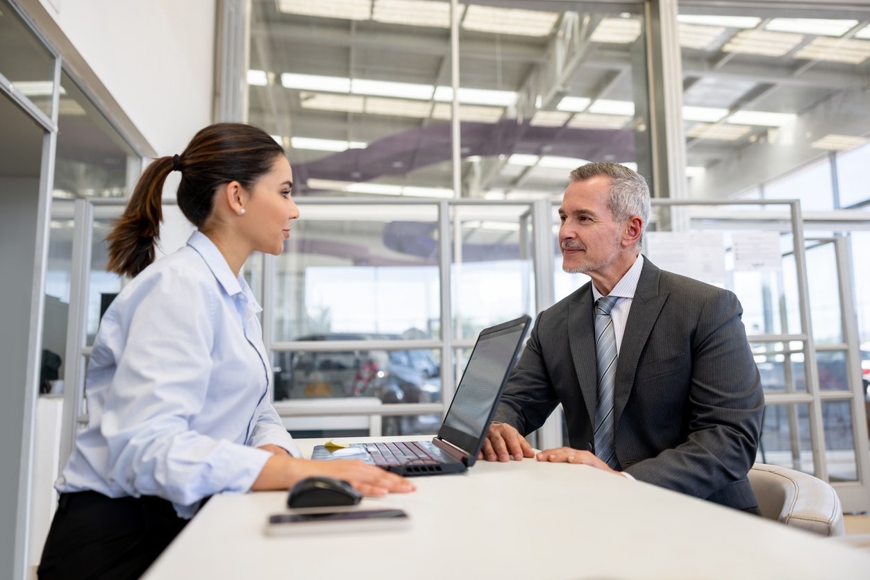 Saleswoman selling a car to a business man at the car dealership Latin American saleswoman selling a car to a business man at the car dealership - car ownership concepts